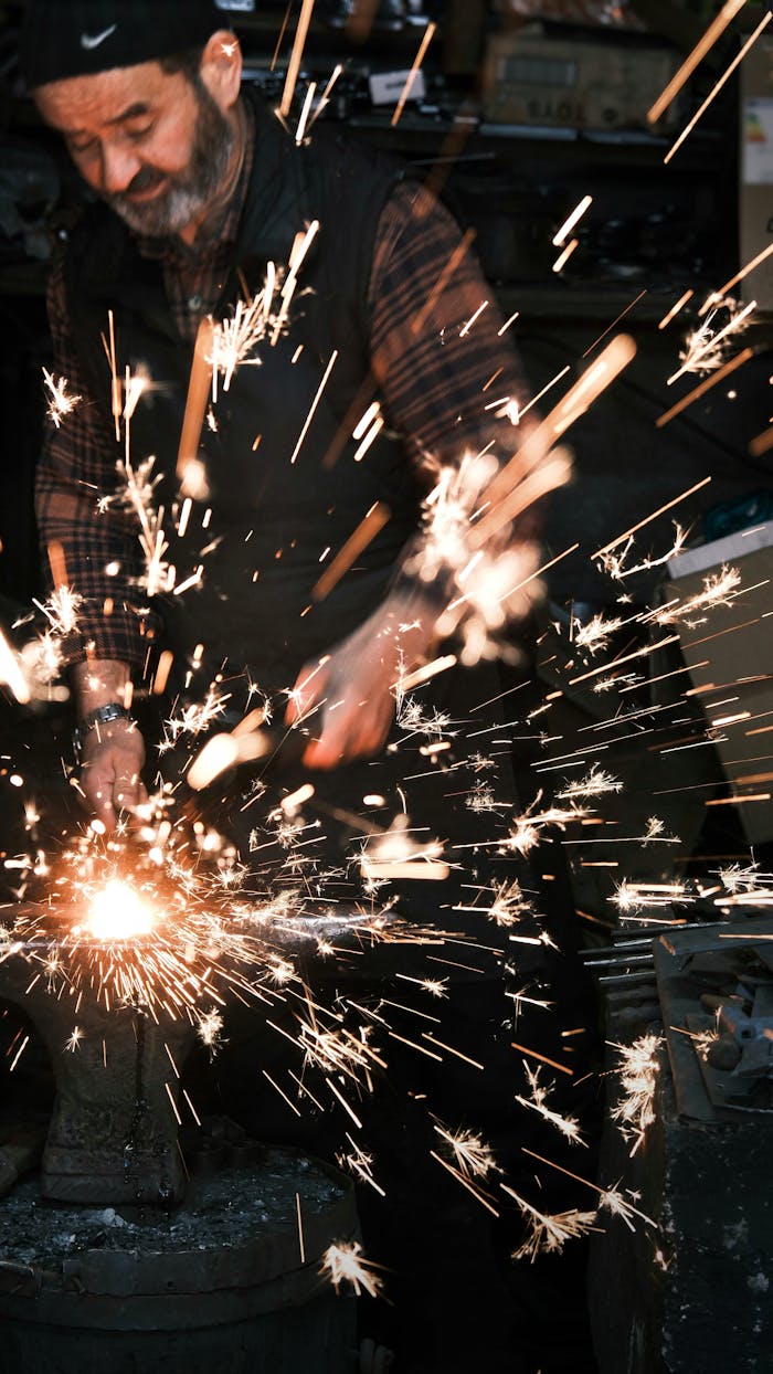 about-02 Adult working with metal, creating bright sparks in an industrial workshop setting.