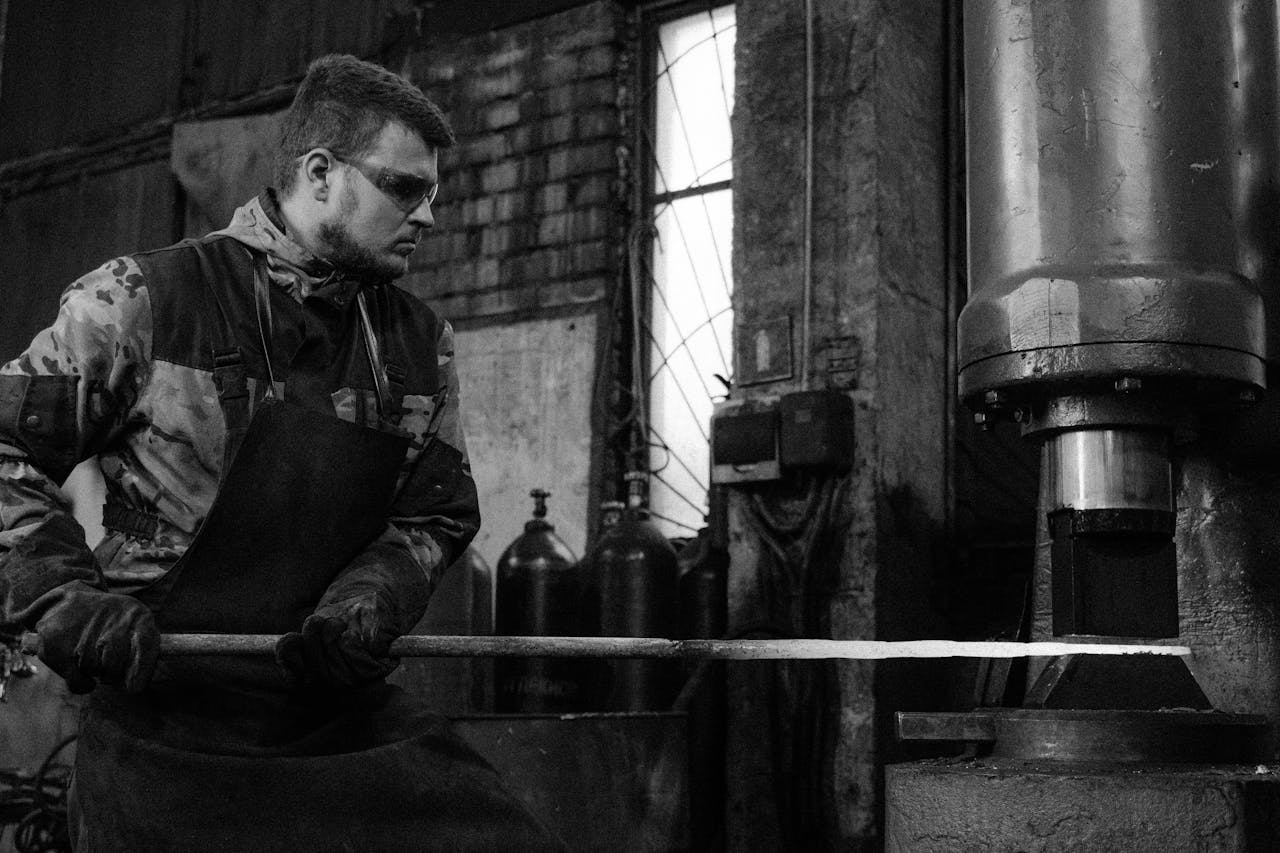 services-img A blacksmith shaping metal using machinery in an industrial workshop.