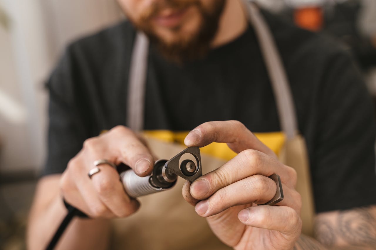 about-img Close-up of a craftsman using a rotary tool for precise metalworking. Focus on craftsmanship.